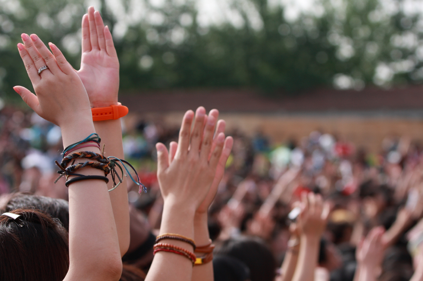 A crowd of hands clapping along to music at a festival